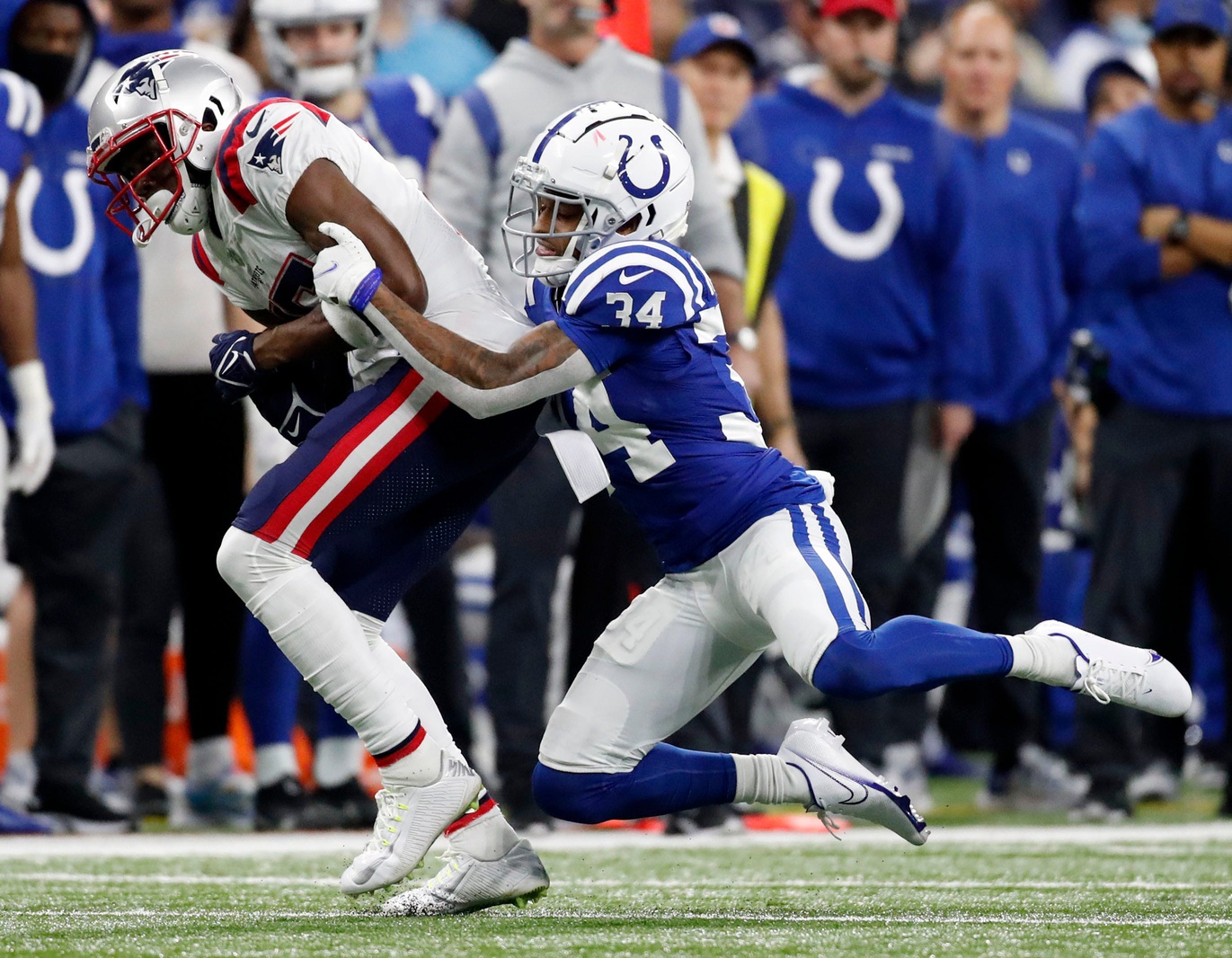 Indianapolis Colts cornerback Isaiah Rodgers (34) wraps up New England Patriots wide receiver Nelson Agholor (15) on Saturday, Dec. 18, 2021, during a game against the New England Patriots at Lucas Oil Stadium in Indianapolis.