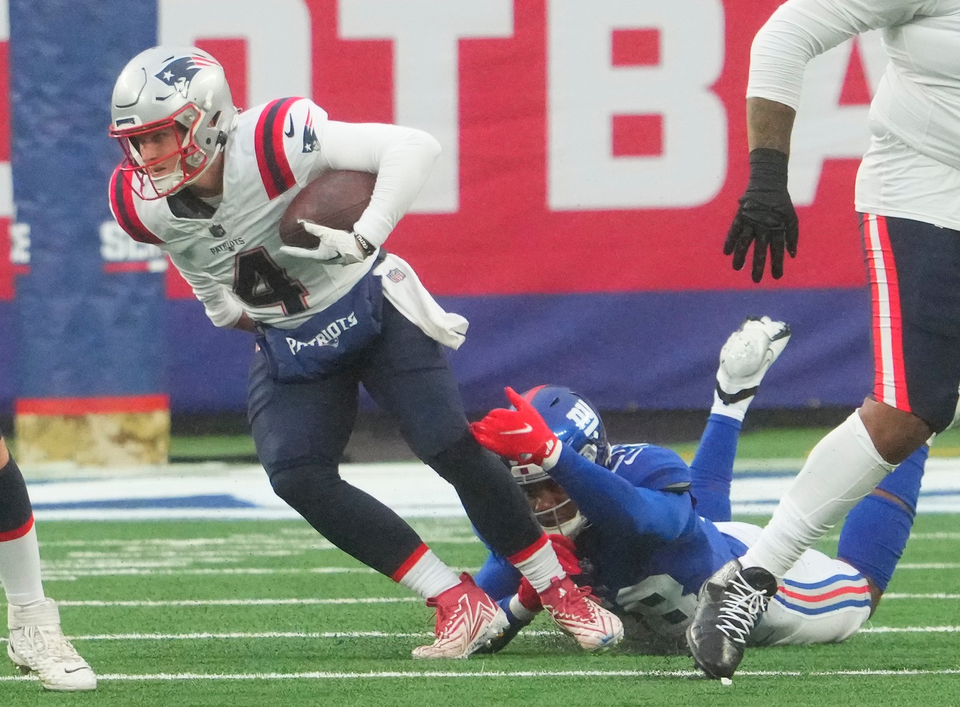 Nov 26, 2023; East Rutherford, New Jersey, USA; New England Patriots quarterback Bailey Zappe (4) breaks free of New York Giants linebacker Bobby Okereke (58) in the 3rd quarter at MetLife Stadium. Mandatory Credit: Robert Deutsch-USA TODAY Sports