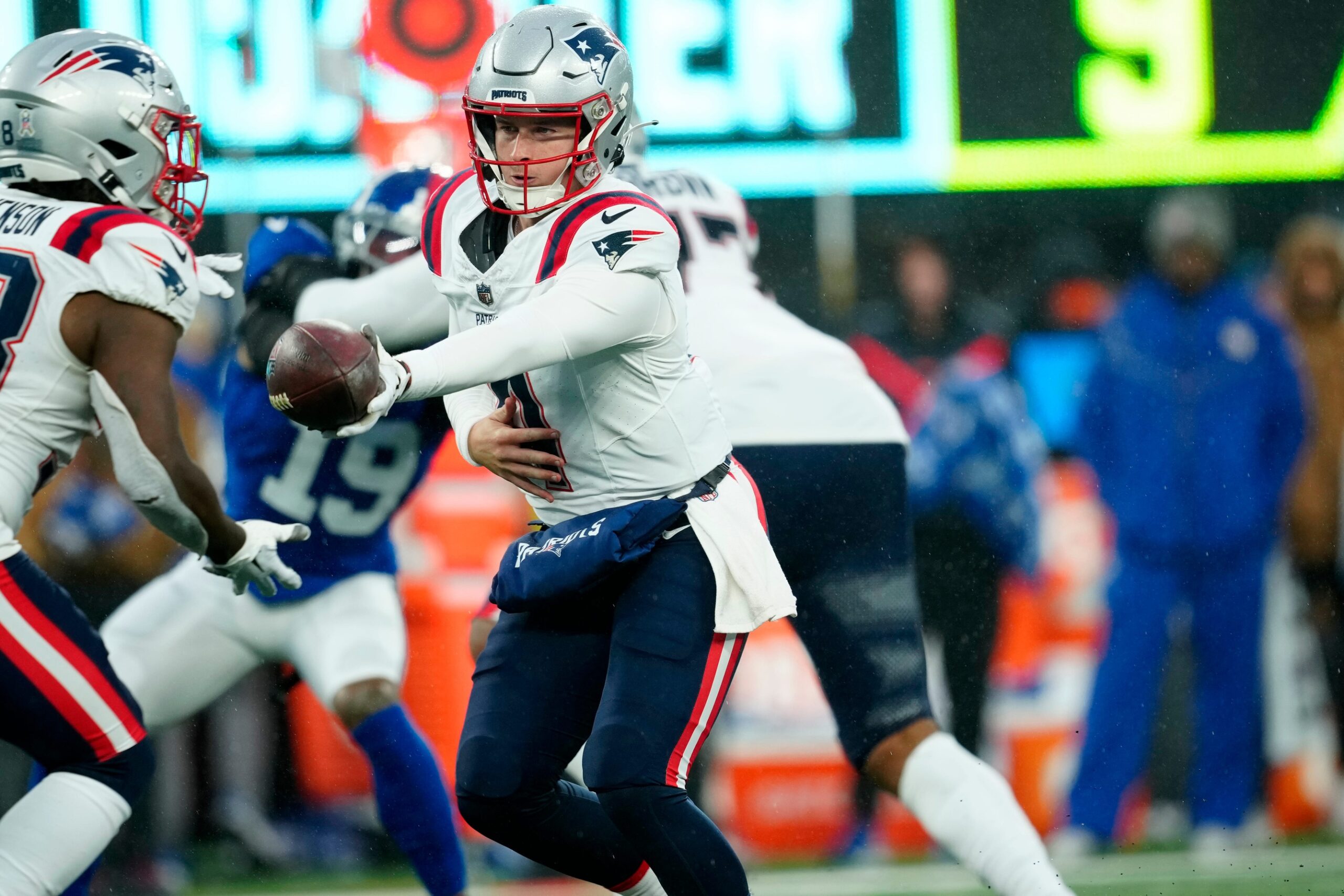 New England Patriots quarterback Bailey Zappe (4) prepares to handoff to New England Patriots running back Rhamondre Stevenson (38) during the second half, Sunday, November 26, 2023.