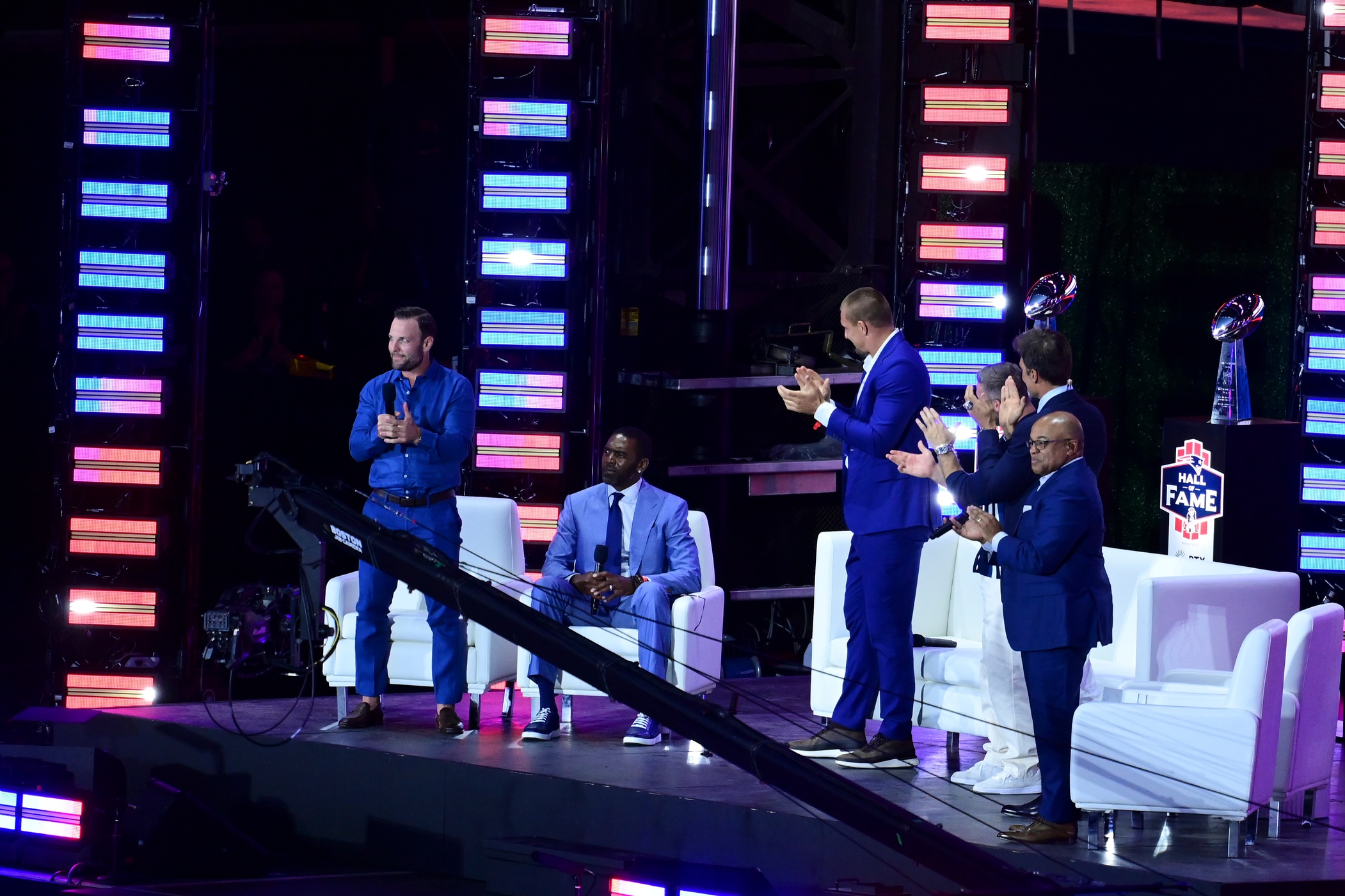 Jun 12, 2024; Foxborough, MA, USA; Former NFL wide receiver Randy Moss (seated) receives a standing ovation from former teammates (left to right) Wes Welker, Rob Gronkowski, Julien Edelman, and Tom Brady during the New England Patriots Hall of Fame induction Ceremony for Tom Brady at Gillette Stadium.  Mandatory Credit: Eric Canha-USA TODAY Sports