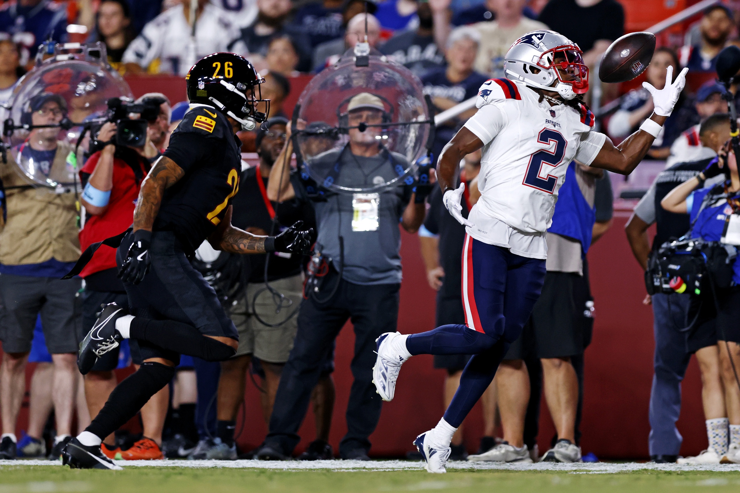 Aug 25, 2024; Landover, Maryland, USA; New England Patriots wide receiver K.J. Osborn (2) tries to make a one handed catch against Washington Commanders cornerback Tariq Castro-Fields (26) during the first quarter during a preseason game at Commanders Field. Mandatory Credit: Peter Casey-USA TODAY Sports