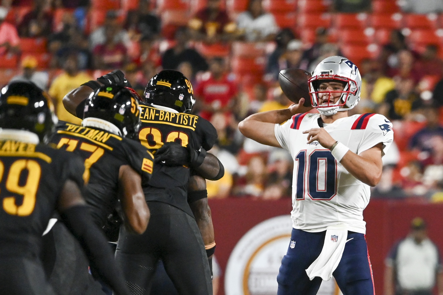 Aug 25, 2024; Landover, Maryland, USA;  New England Patriots quarterback Drake Maye (10) throws off his back foot as Washington Commanders defense applies pressure during the first half at Commanders Field. Mandatory Credit: Tommy Gilligan-USA TODAY Sports