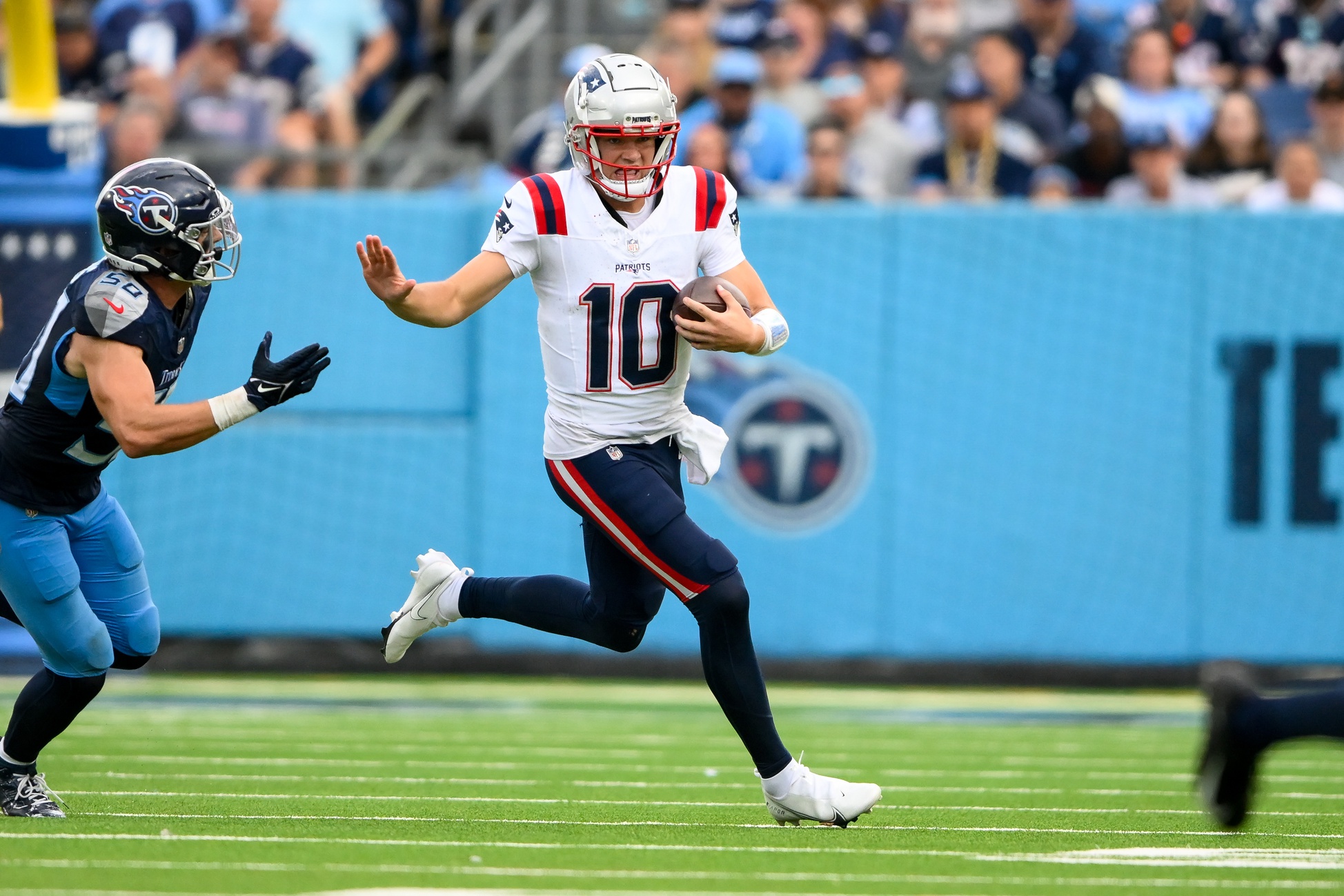 Nov 3, 2024; Nashville, Tennessee, USA; New England Patriots quarterback Drake Maye (10) stiff arms Tennessee Titans linebacker Harold Landry III (58) during the second half at Nissan Stadium. Mandatory Credit: Steve Roberts-Imagn Images