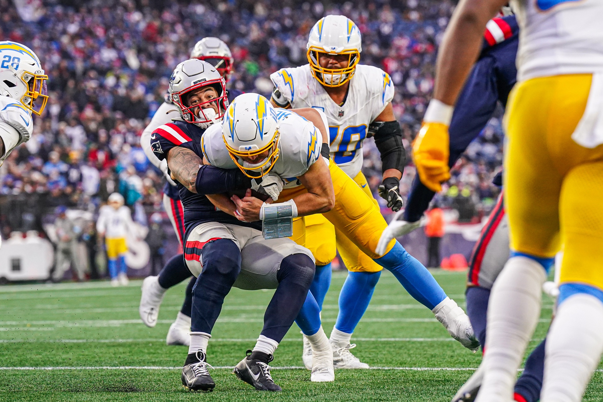Dec 28, 2024; Foxborough, Massachusetts, USA; Los Angeles Chargers quarterback Justin Herbert (10) runs the ball against New England Patriots linebacker Sione Takitaki (16) in the third quarter at Gillette Stadium. Mandatory Credit: David Butler II-Imagn Images