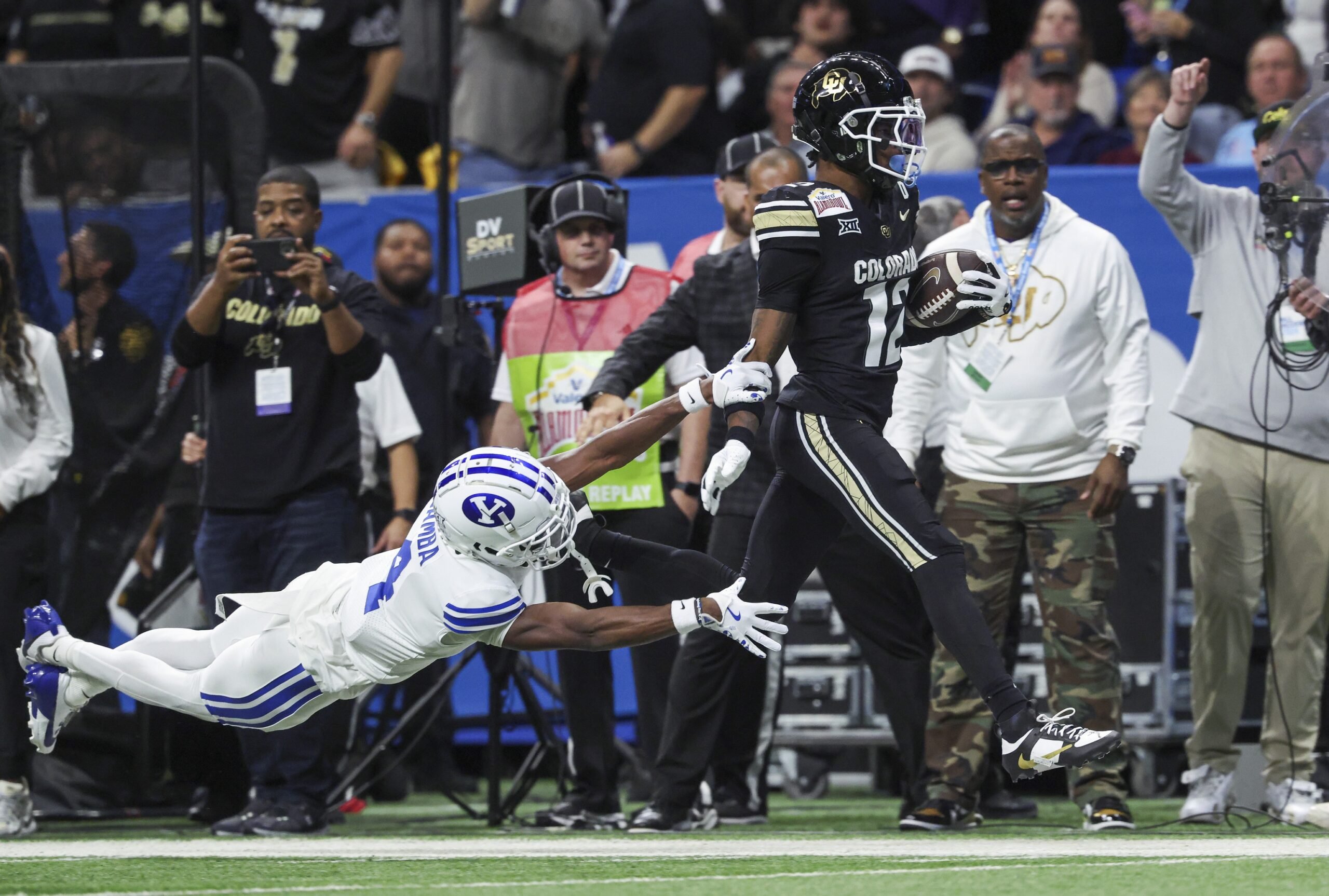 Dec 28, 2024; San Antonio, TX, USA; Colorado Buffaloes wide receiver Travis Hunter (12) runs with the ball as Brigham Young Cougars cornerback Mory Bamba (4) attempts to make a tackle during the second quarter at Alamodome. Mandatory Credit: Troy Taormina-Imagn Images
