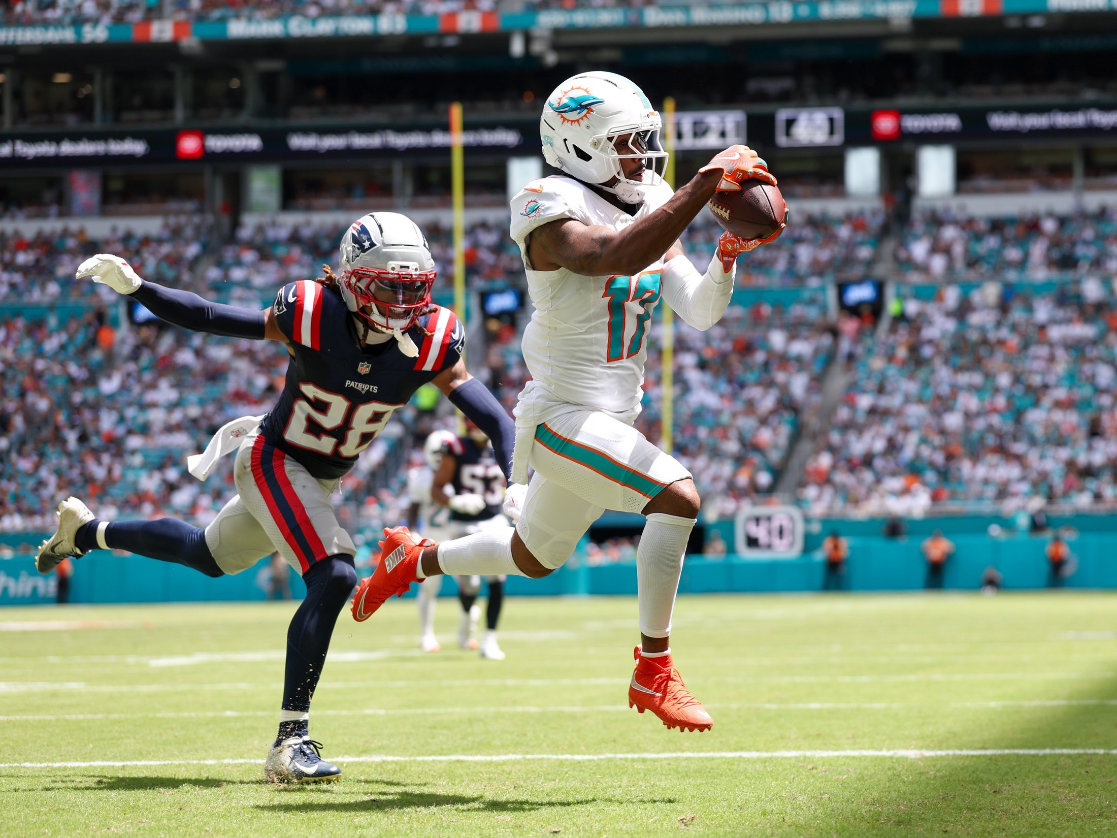Sep 14, 2025; Miami Gardens, Florida, USA; Miami Dolphins wide receiver Jaylen Waddle (17) catches a pass for a touchdown defended by New England Patriots cornerback Alex Austin (28) in the second quarter  at Hard Rock Stadium. Mandatory Credit: Nathan Ray Seebeck-Imagn Images