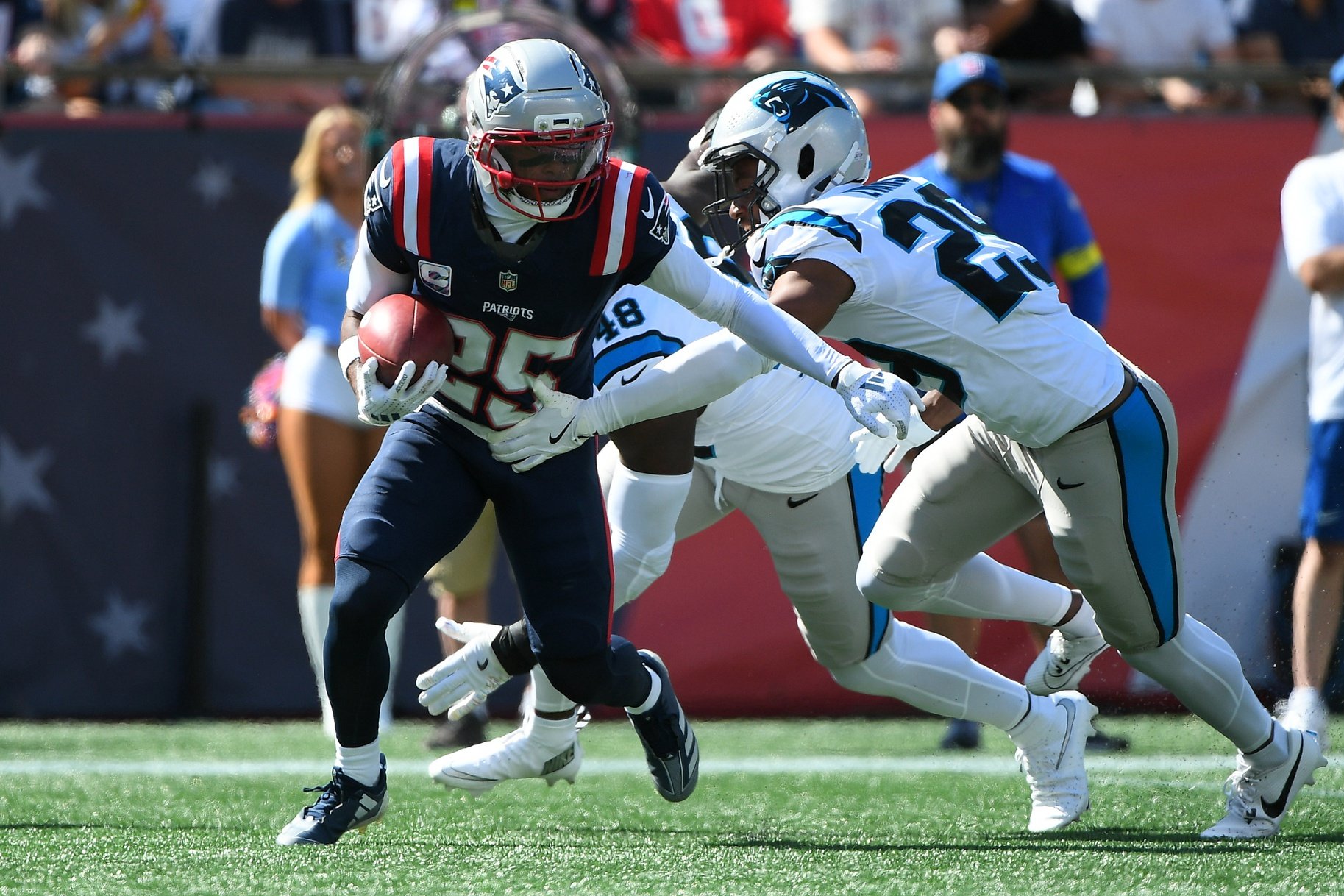 Sep 28, 2025; Foxborough, Massachusetts, USA; New England Patriots cornerback Marcus Jones (25) returns a punt while Carolina Panthers cornerback Akayleb Evans (29) defends during the first half at Gillette Stadium. Mandatory Credit: Bob DeChiara-Imagn Images