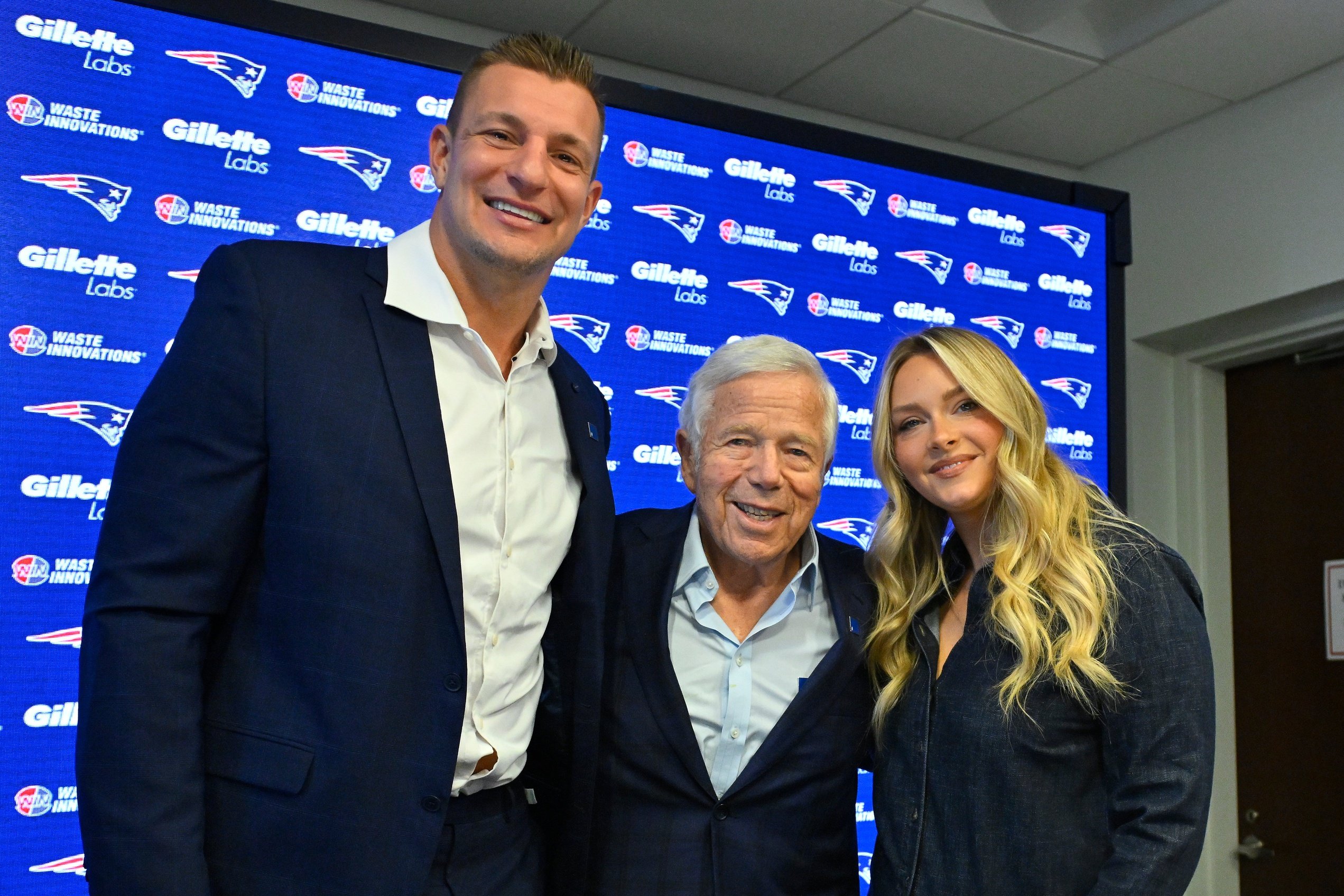 Nov 12, 2025; Foxborough, MA, USA; Rob Gronkowski, Patriots owner Robert Kraft and Camille Kostek pose for a photograph after press conference where Gronkowski signed a one day ceremonial contract at Gillette Stadium. Mandatory Credit: Eric Canha-Imagn Images