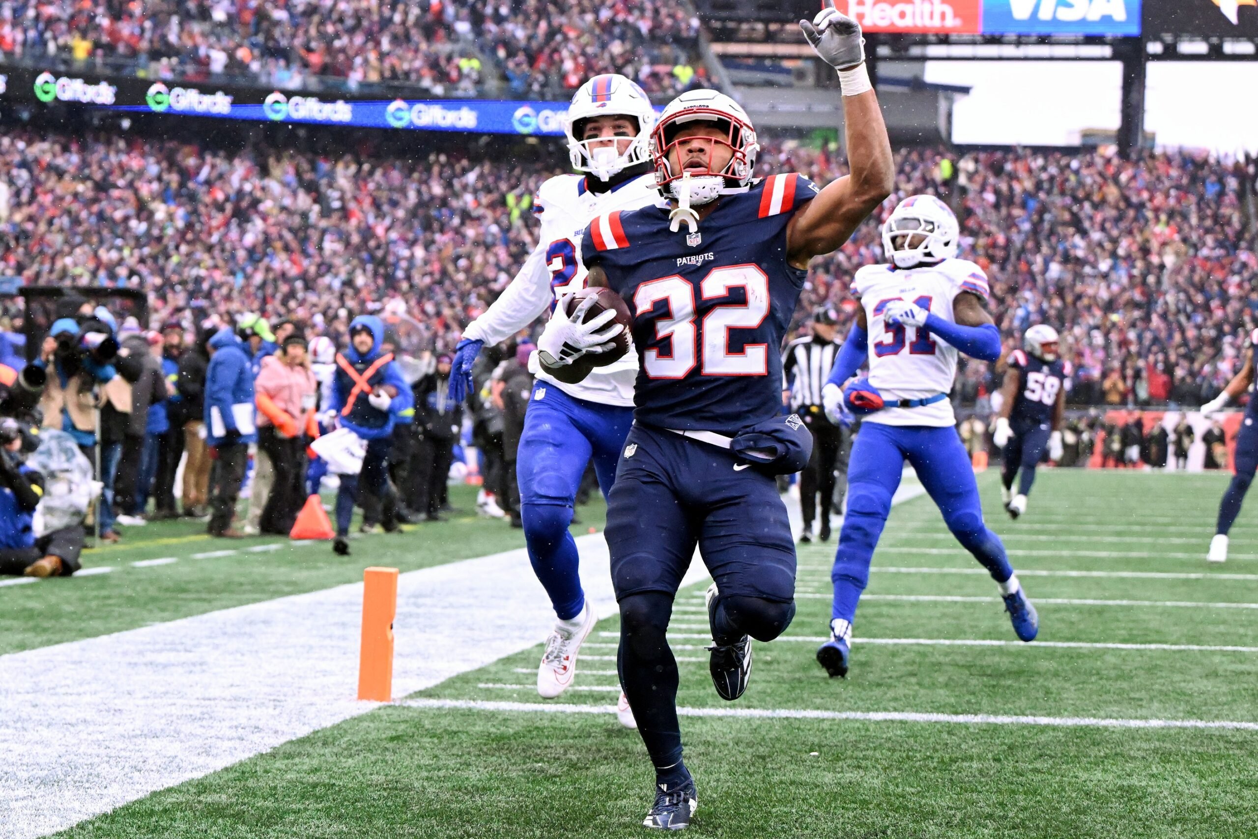 Dec 14, 2025; Foxborough, Massachusetts, USA; New England Patriots running back Treveyon Henderson (32) scores a touchdown against the Buffalo Bills during the first half at Gillette Stadium. Mandatory Credit: Brian Fluharty-Imagn Images