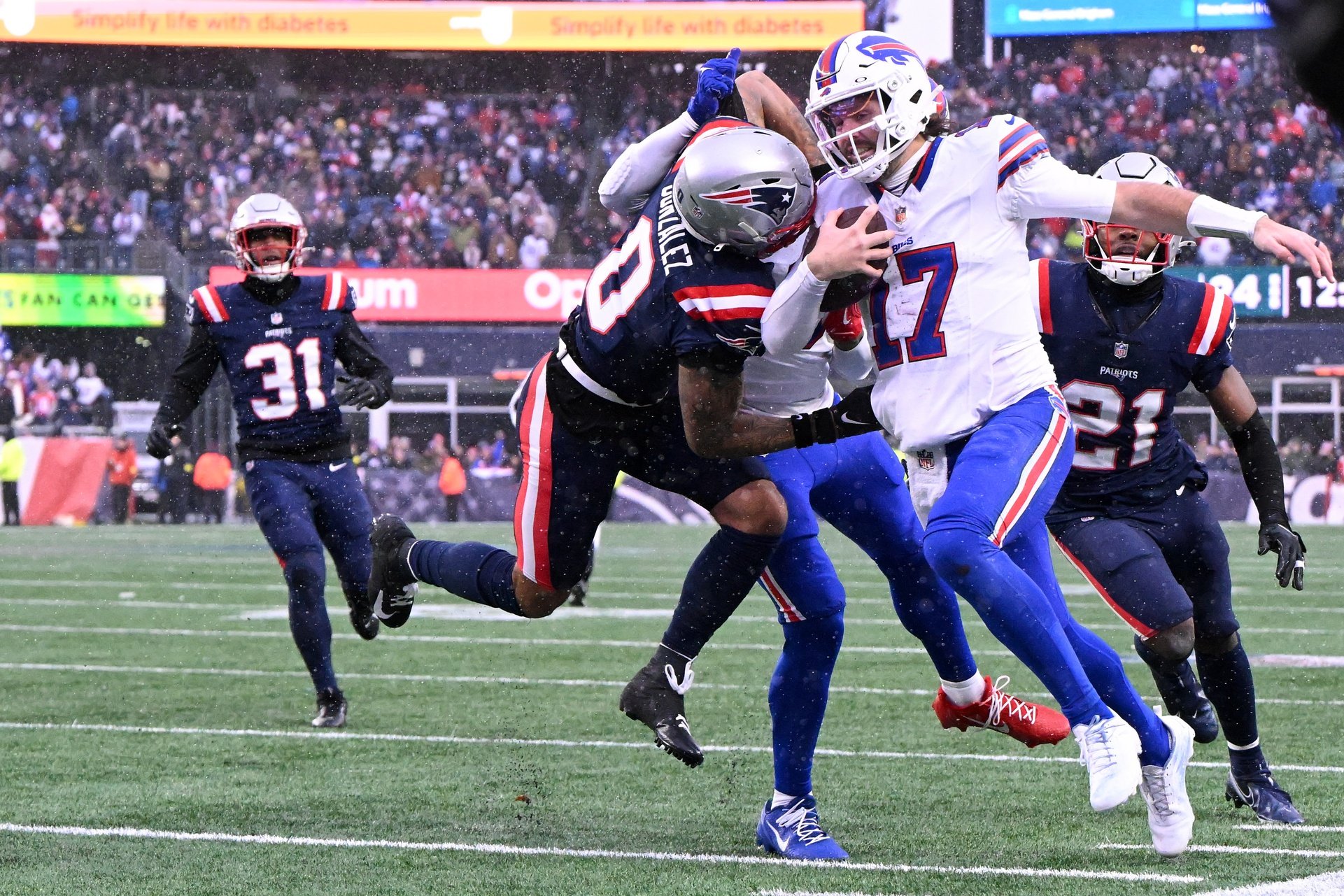 Dec 14, 2025; Foxborough, Massachusetts, USA; New England Patriots cornerback Christian Gonzalez (0) pushes Buffalo Bills quarterback Josh Allen (17) out of bounds  during the second half at Gillette Stadium. Mandatory Credit: Brian Fluharty-Imagn Images