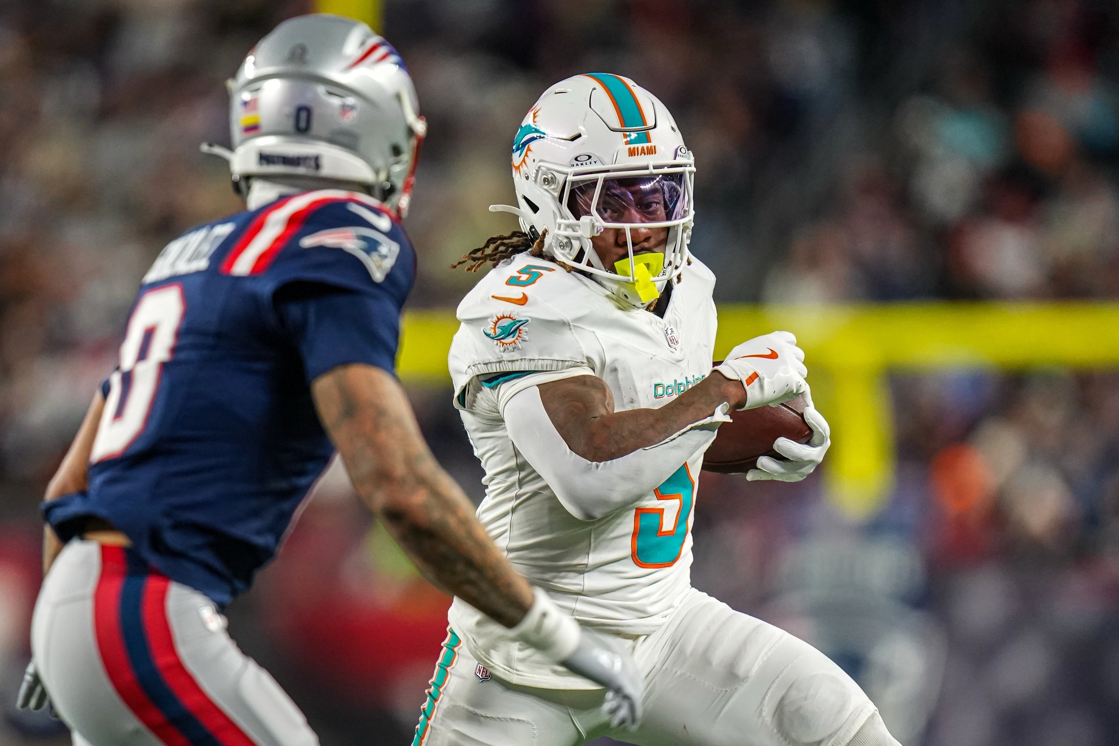 Jan 4, 2026; Foxborough, Massachusetts, USA; Miami Dolphins running back Jaylen Wright (5) runs the ball against New England Patriots cornerback Christian Gonzalez (0) during the second quarter at Gillette Stadium. Mandatory Credit: David Butler II-Imagn Images