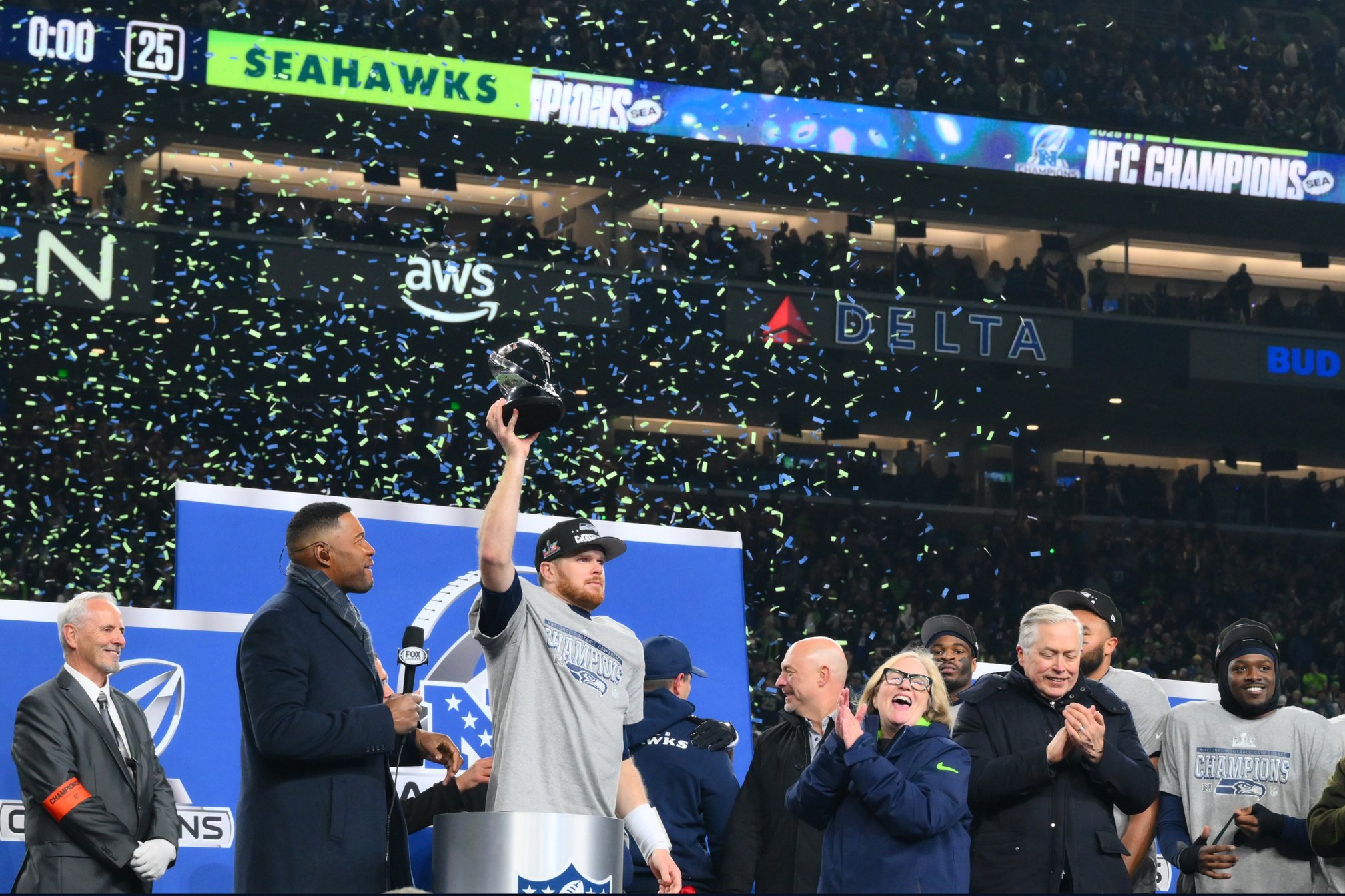 Jan 25, 2026; Seattle, WA, USA; Seattle Seahawks quarterback Sam Darnold (14) celebrates with the trophy on the podium after defeating the Los Angeles Rams in the 2026 NFC Championship Game at Lumen Field. Mandatory Credit: Steven Bisig-Imagn Images